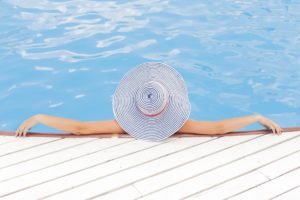 woman lounging in a pool with a sun hat